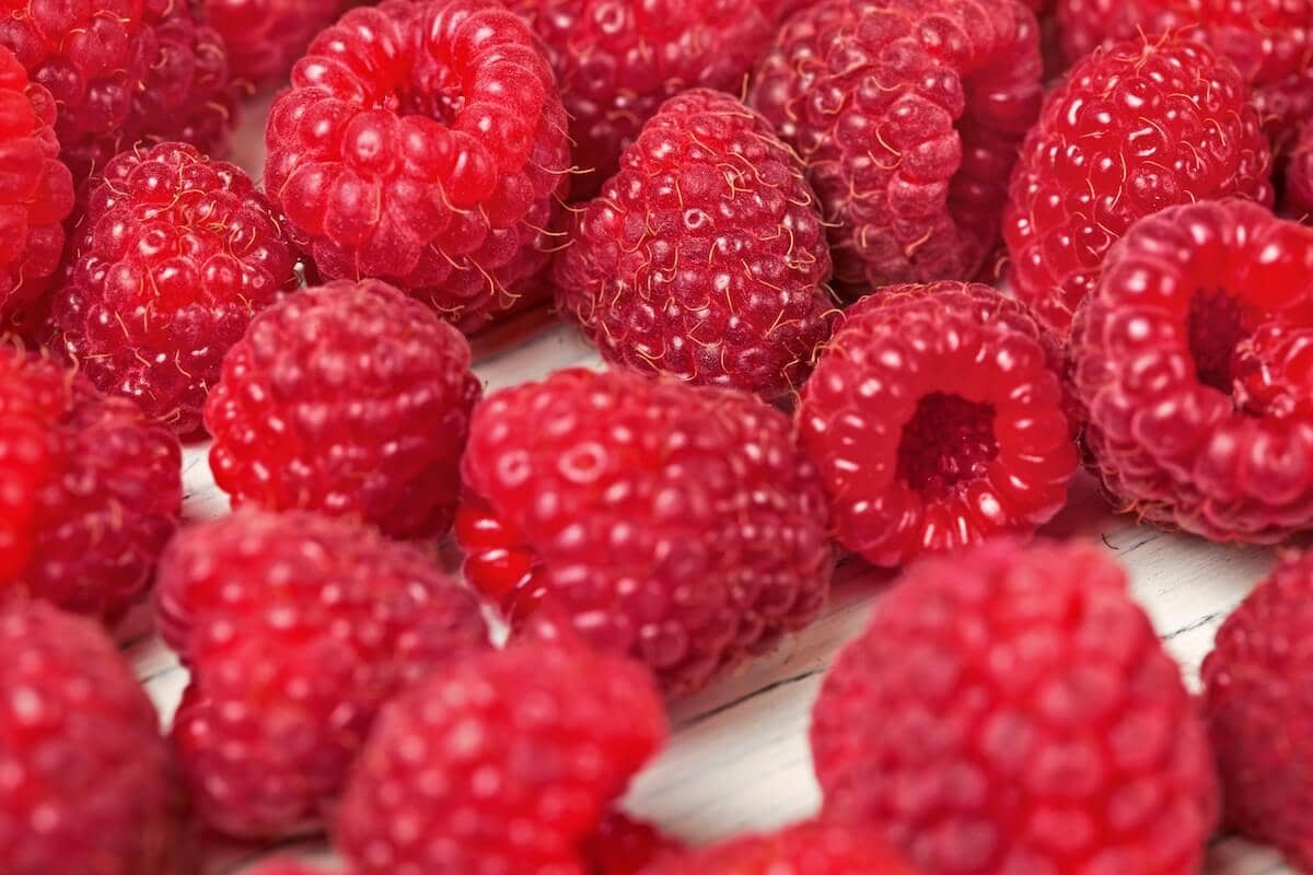 Close Up of Raspberries Scattered on White Boards